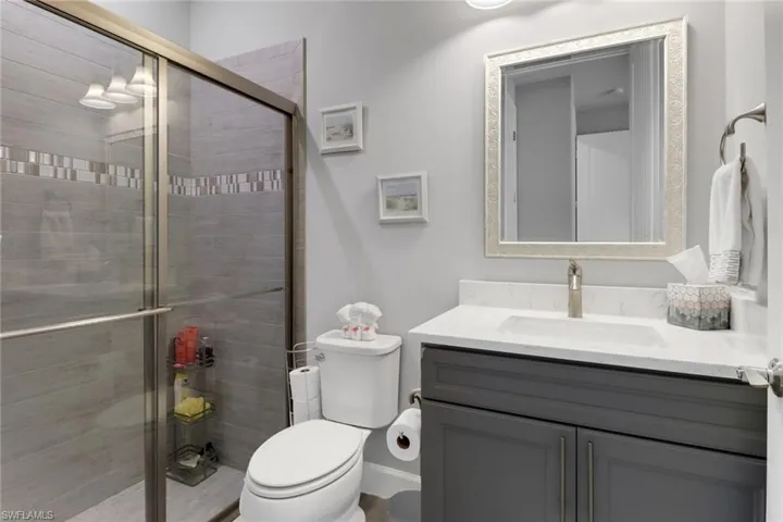 Bathroom with toilet, a shower with shower door, and vanity