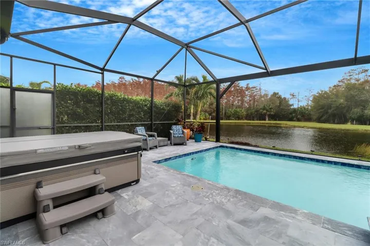 View of swimming pool with a water view, a patio area, a lanai, and a hot tub