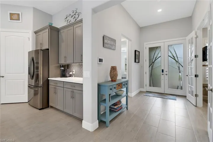 Kitchen with french doors, stainless steel refrigerator with ice dispenser, gray cabinetry, and backsplash