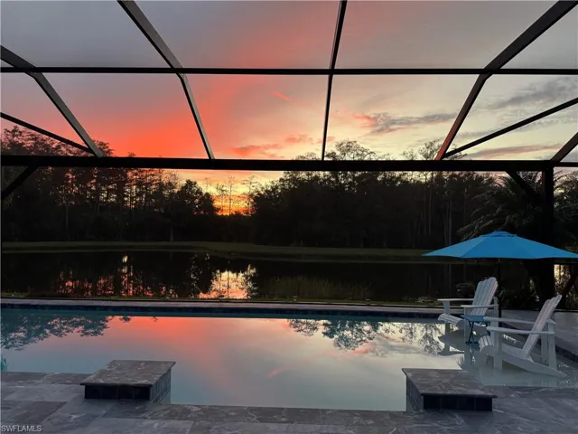 Pool at dusk with a water view, a patio, and a lanai
