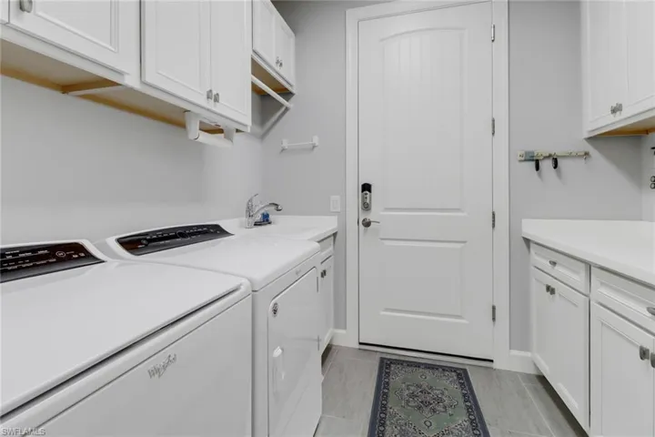 Clothes washing area with cabinets, sink, and separate washer and dryer
