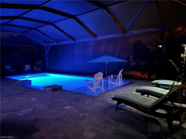 View of pool featuring a patio, glass enclosure, and a jacuzzi
