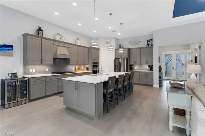 Kitchen featuring gray cabinets, wine cooler, custom range hood, and stainless steel appliances