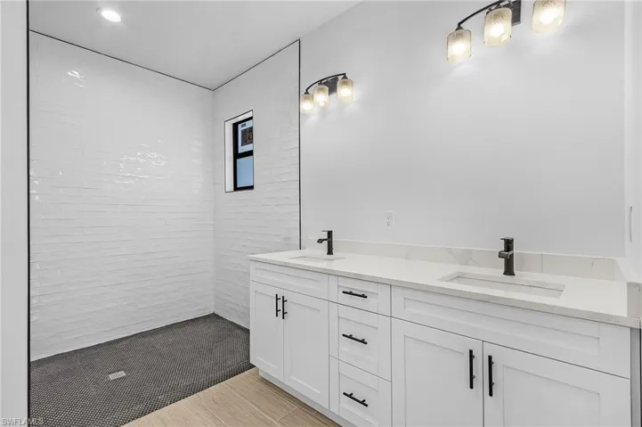 Bathroom featuring a tile shower, vanity, and hardwood / wood-style floors