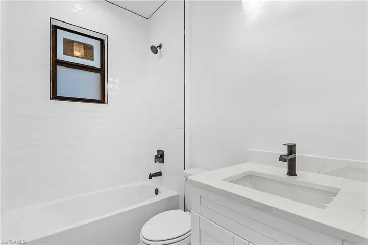 Full bathroom featuring tiled shower / bath combo, vanity, and toilet