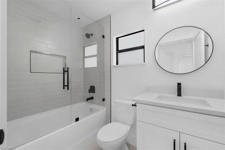 Bathroom featuring a tub/shower combination with glass enclosure, subway tile surround, and built-in niche