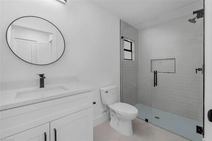 Modern bathroom featuring a frameless glass shower enclosure with subway tile surround, a built-in shower niche, and a matte black shower head