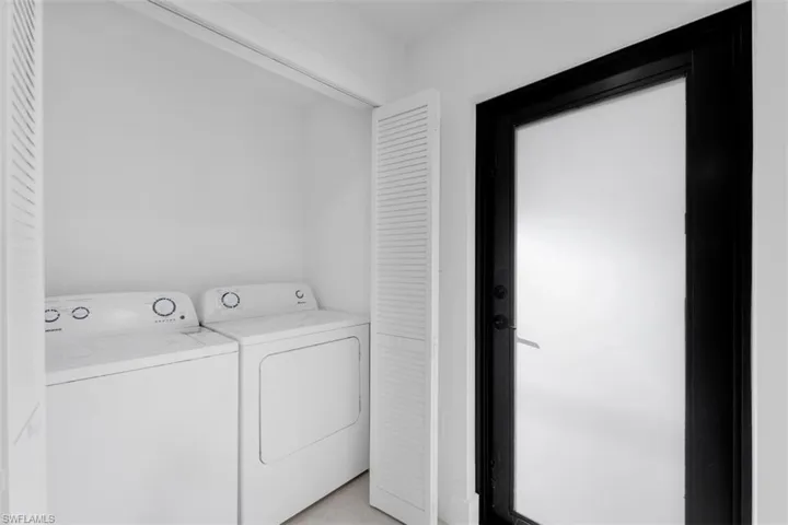 Dedicated laundry closet featuring a built-in washer and dryer set, bi-fold louvered doors, and a frosted glass door with a dark frame