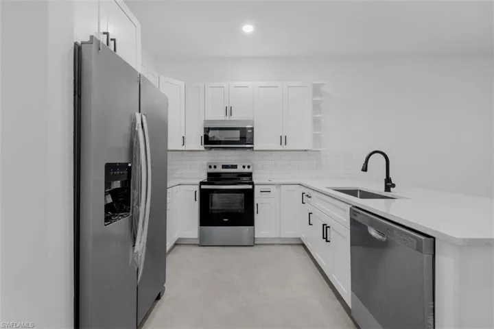 Contemporary kitchen featuring white cabinetry, stainless steel appliances, light-toned countertops, and a subway tile backsplash