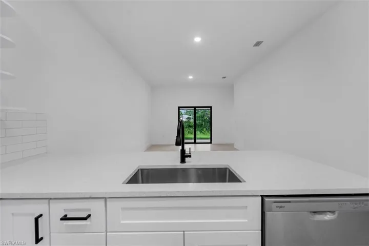 Modern kitchen island featuring a stainless steel undermount sink, matte black faucet, and white countertop