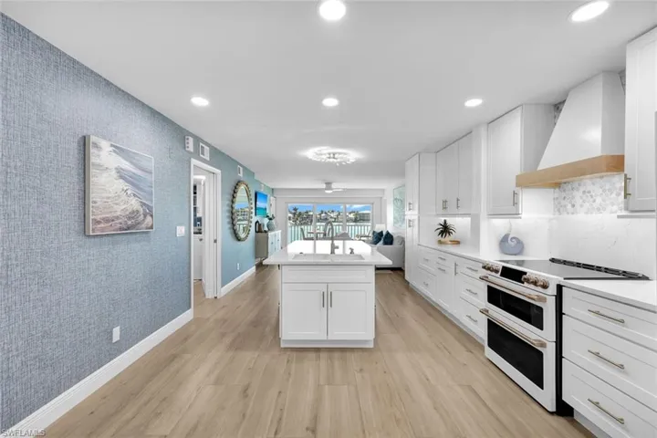 Kitchen featuring white cabinets, double oven range, a center island, custom range hood, and light hardwood / wood-style flooring