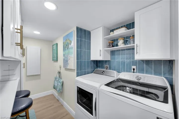 Laundry room featuring independent washer and dryer, cabinets, and light hardwood / wood-style flooring