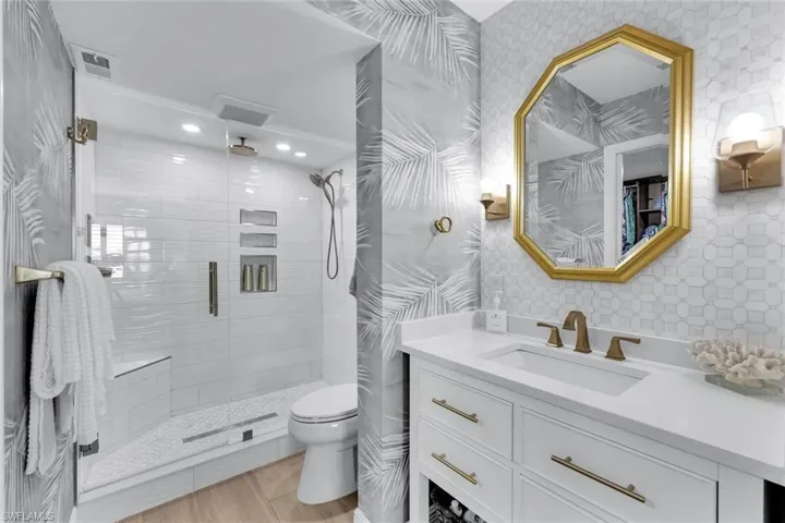 Bathroom with vanity, an enclosed shower, and toilet