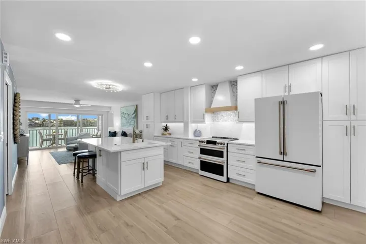Kitchen with a breakfast bar, high quality appliances, white cabinetry, custom exhaust hood, and a center island