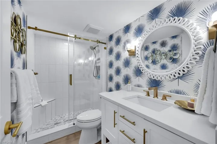 Bathroom featuring a shower with door, vanity, wood-type flooring, and toilet
