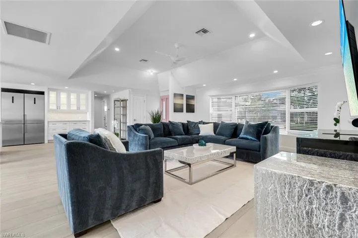 Living room featuring recessed lighting, light wood finished floors, ceiling fan, and a raised ceiling