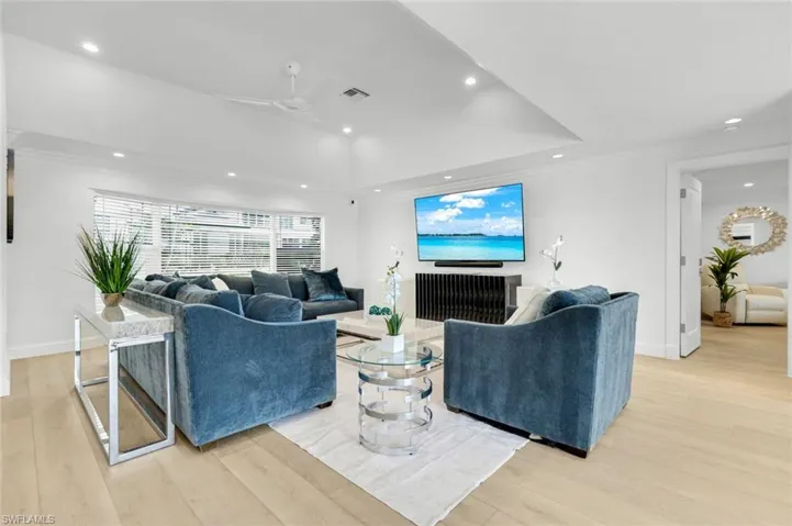 Living area featuring recessed lighting, light wood-style floors, a tray ceiling, a ceiling fan, and ornamental molding