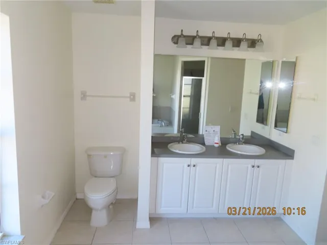 Full bath featuring double vanity and light tile patterned flooring