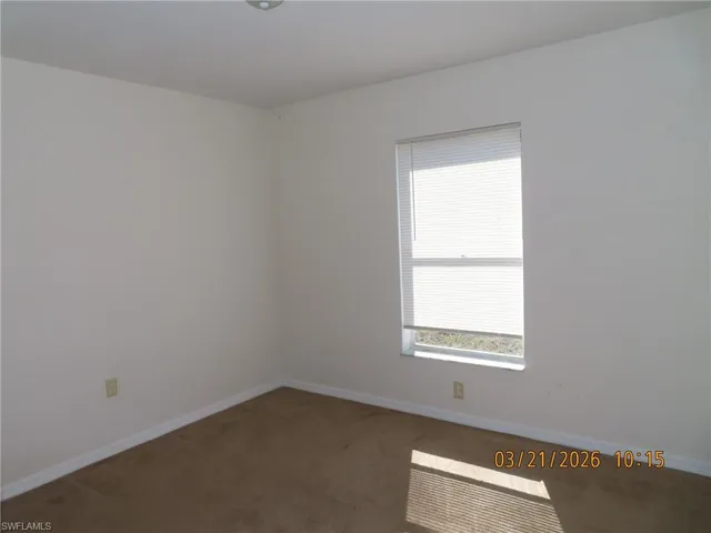 Spare room featuring dark colored carpet and baseboards