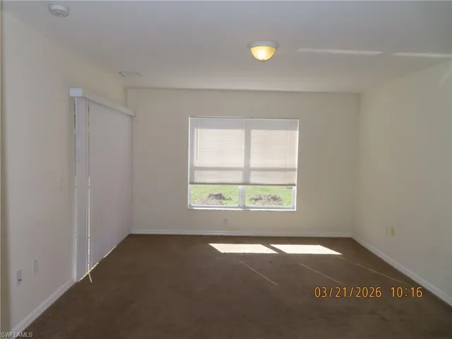 Empty room featuring dark colored carpet and baseboards