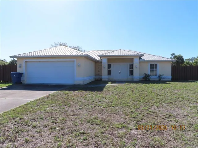 Single story home with an attached garage, driveway, stucco siding, and a metal roof
