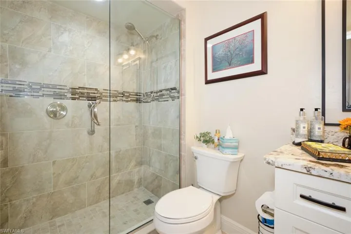 Bathroom with vanity, toilet, and a shower with door