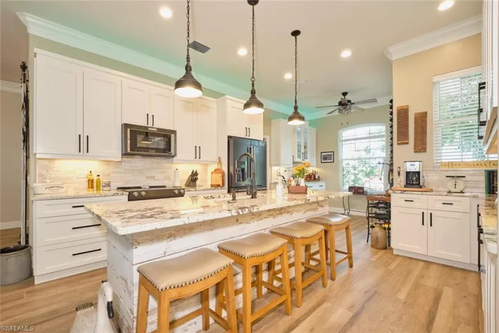 Kitchen with light hardwood / wood-style flooring, white cabinetry, a kitchen island with sink, and stainless steel fridge with ice dispenser