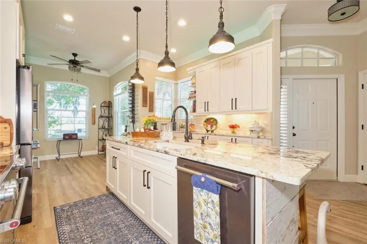Kitchen featuring dishwasher, white cabinetry, an island with sink, and crown molding