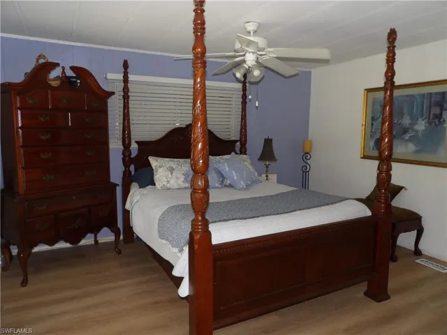 Bedroom featuring ceiling fan, light wood-style floors, and wooden walls