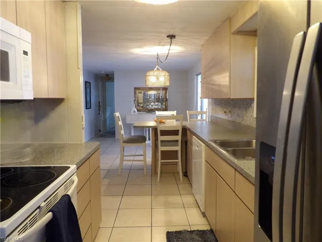 Kitchen featuring light cabinets, light tile patterned floors, pendant lighting, and backsplash