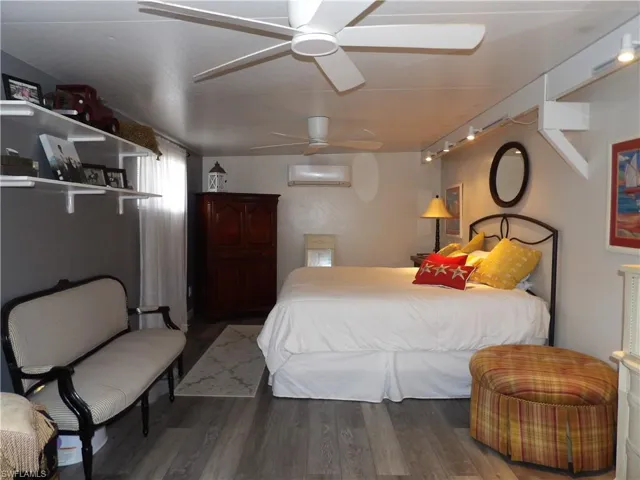 Bedroom with wood finished floors, rail lighting, ceiling fan, and a wall mounted air conditioner