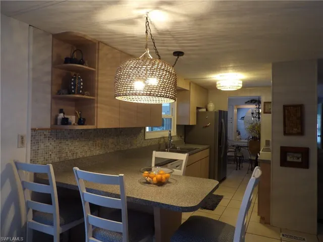 Kitchen featuring a kitchen breakfast bar, a peninsula, decorative light fixtures, open shelves, and light tile patterned flooring