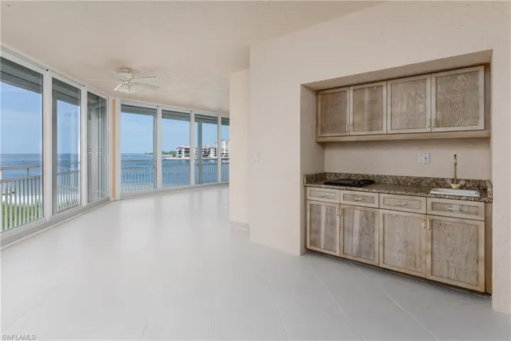 Kitchen featuring a water view, ceiling fan, light brown cabinets, light tile patterned floors, and a wall of windows