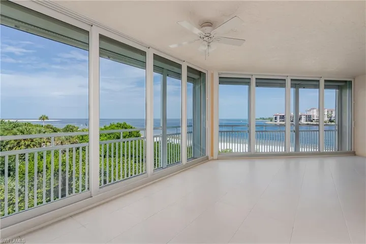 Unfurnished sunroom featuring a wealth of natural light, ceiling fan, and a water view