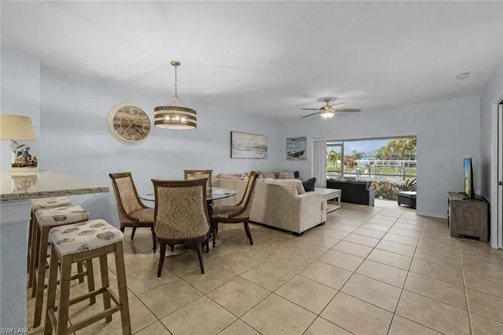 Dining space with light tile patterned flooring, ceiling fan, and a chandelier