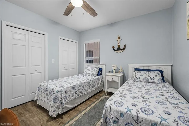 Bedroom with multiple closets, dark wood finished floors, and ceiling fan