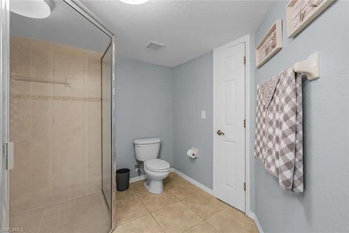 Full bathroom featuring a textured ceiling, light tile patterned floors, and a stall shower