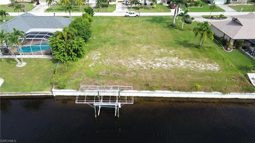 Aerial view of residential area featuring a nearby body of water and a pool