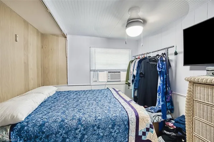 Bedroom featuring a ceiling fan and wooden walls