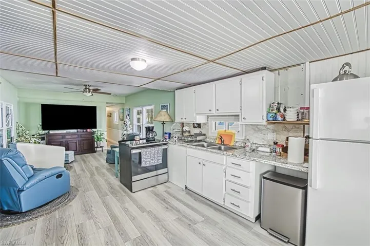 Kitchen featuring freestanding refrigerator, ceiling fan, refrigerator, open floor plan, and electric stove