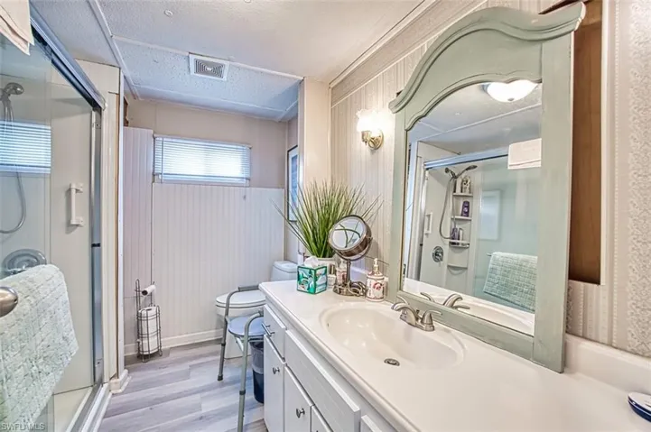 Bathroom with a shower stall, wood finished floors, vanity, and wainscoting