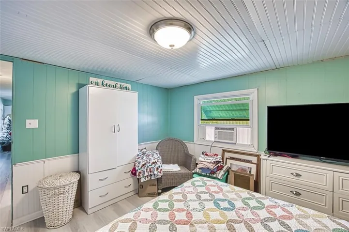 Bedroom with light wood-style floors, cooling unit, and a decorative wall