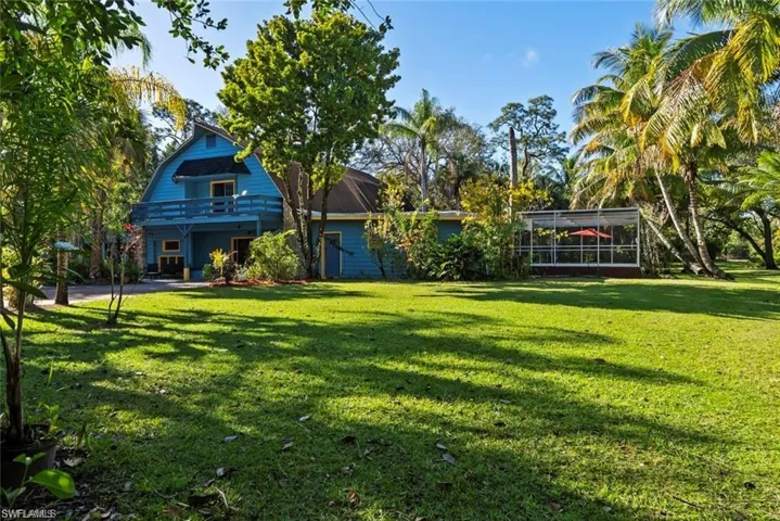 Back of house with a lawn, a patio area, and a gambrel roof