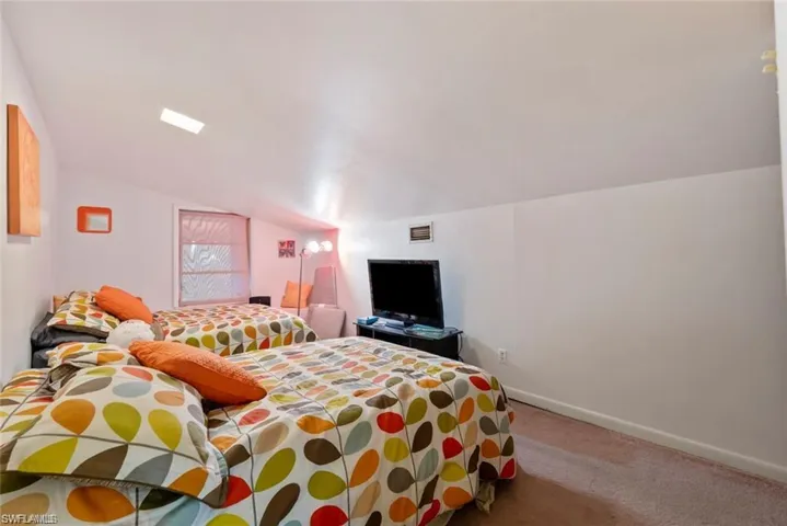 Carpeted bedroom with baseboards and lofted ceiling