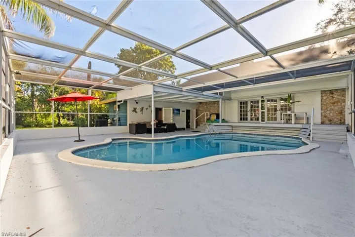 Outdoor pool with a sunroom, a patio area, and glass enclosure