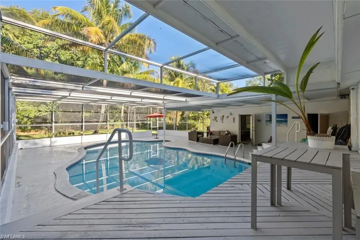 Outdoor pool featuring a patio area, a lanai, a sunroom, and an outdoor living / dining area