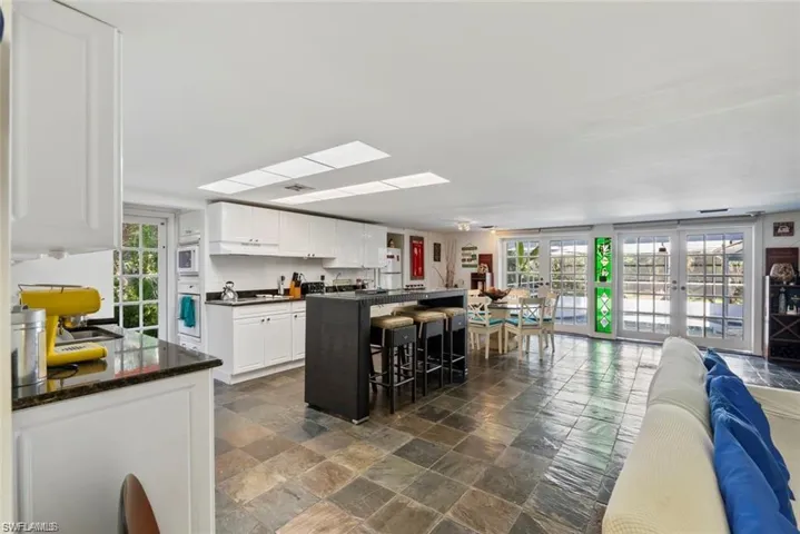 Kitchen featuring open floor plan, dark stone finish flooring, white cabinets, and a breakfast bar area