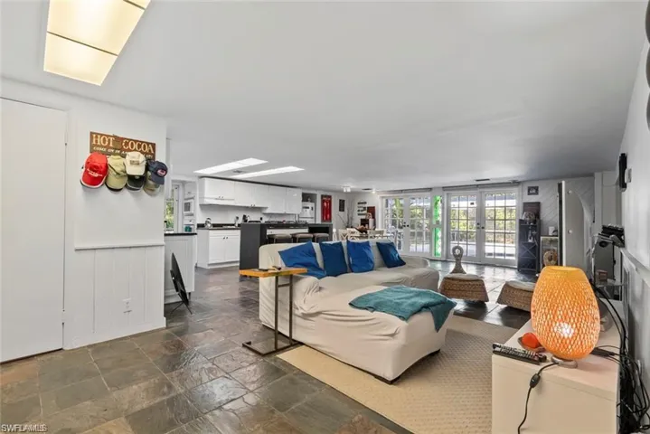 Living room featuring a wainscoted wall, french doors, stone tile floors, and wooden walls
