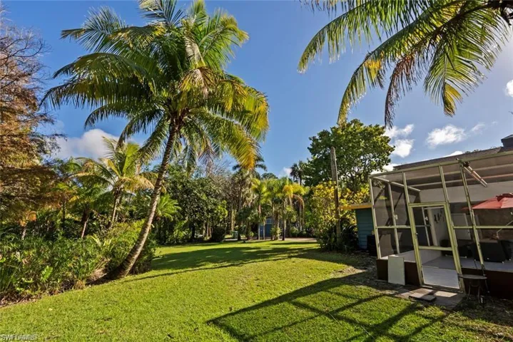 View of green lawn featuring a sunroom and a lanai