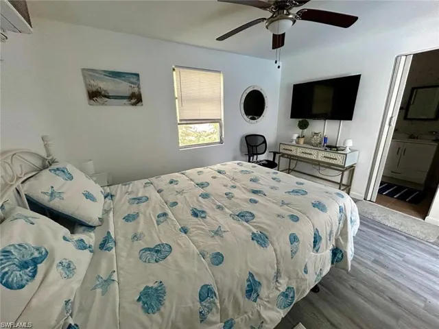 Bedroom featuring wood finished floors, a ceiling fan, and ensuite bath